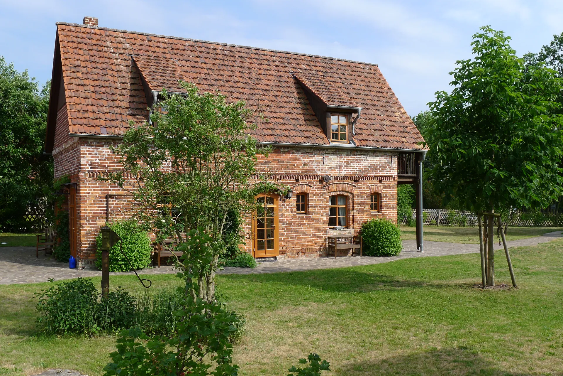 Freistehendes Ferienhaus aus Backstein mit rotem Ziegeldach und Garten