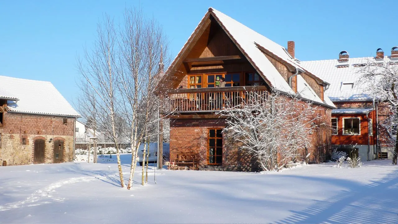 Ferienhaus mit Holzbalkon im Schnee an einem sonnigen Wintertag